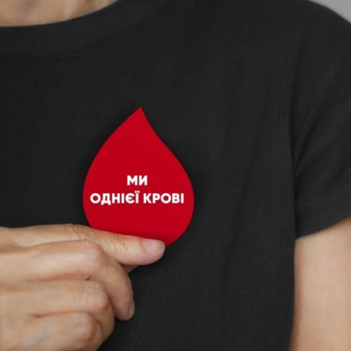 Red blood drop badge with the Ukrainian slogan “We are of one blood.”